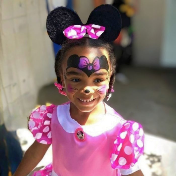 A girl in Minnie Mouse face painting at a party